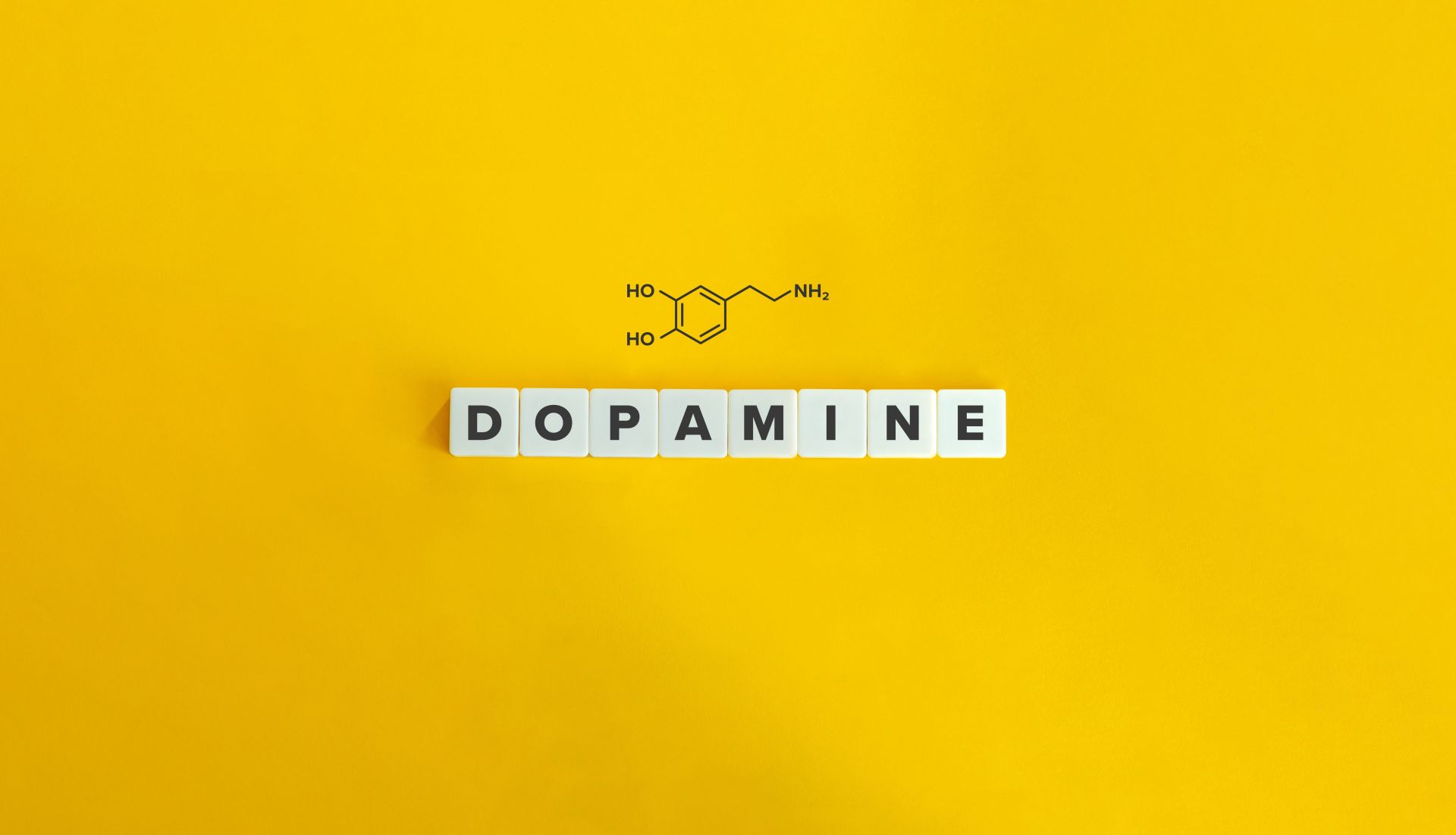 Wzór chemiczny dopaminy z napisem dopamine na żółtym tle